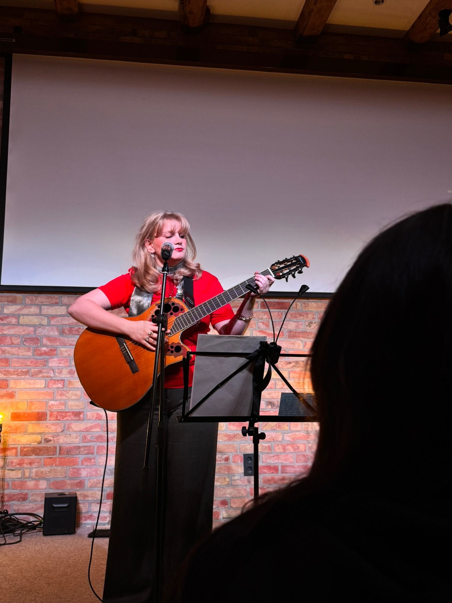 Singer- Singwriterin Mansko mit Gitarre auf einer Bühne.