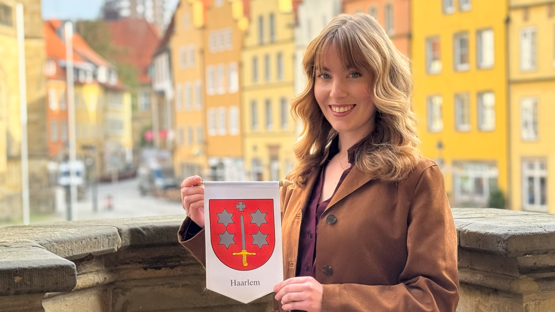 Städtebotschafterin Emma Bos mit dem Wimpel der stadt Haarlem auf der Treppe des Osnabrücker Rathauses